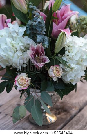 Wedding bouquet of white and pink flowers including roses, hydrangea, star gazer lilies and queen annes lace on a rustic table in the French countryside on Valentine's Day