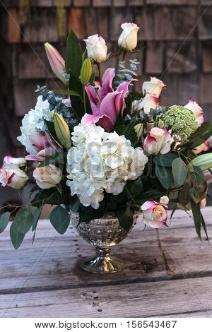 Wedding bouquet of white and pink flowers including roses, hydrangea, star gazer lilies and queen annes lace on a rustic table in the French countryside on Valentine's Day
