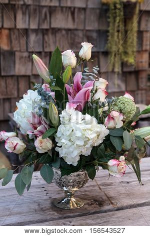 Wedding bouquet of white and pink flowers including roses, hydrangea, star gazer lilies and queen annes lace on a rustic table in the French countryside on Valentine's Day