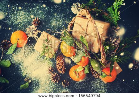 Christmas New Year Composition with Tangerines Boxes Pine cones Greens in Basket Black Background Holiday Decoration to Russian Tradition Toned Drawing Snowfall