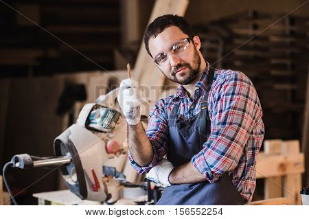Master sells its own products. Male carpenter have an idea at workshop holding pen in his hand.