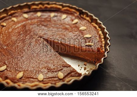 Homemade pumpkin pie decorated with seeds closeup selective focus. Traditional thanksgiving food.