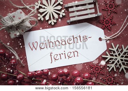 Nostalgic Christmas Decoration Like Gift Or Present, Sleigh. Card For Seasons Greetings With Red Paper Background. German Text Weihnachtsferien Means Christmas Break