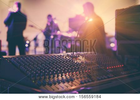 Soundman working on the mixing console in concert hall