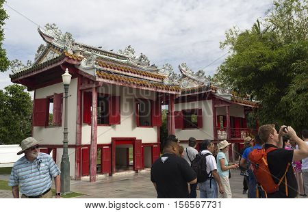 AYUTTHAYA, THAILAND - November 4, 2016: People standing in front of two little Chinese style structures admiring the royal mansion at the Bang Pa-In summer palace in Thailand
