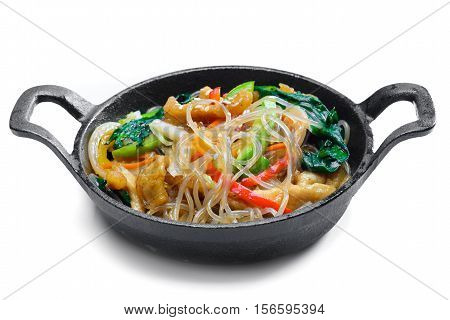 Korean rice noodle with vegetables on frying pan on white background