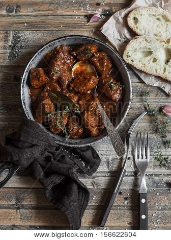 Beef stew in a frying pan on a wooden rustic table. Top view