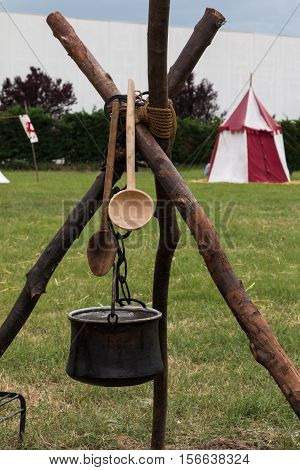 Black Pettle and Wooden Spoon after Bonfire on Tripod White and Red Tent in background