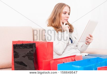 Lady Laying On Chouch Holding Tablet Being Pensive