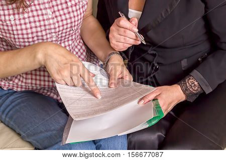 The insurance agent makes a deal sign documents. The tablet in female hands. A woman touching the screen with her finger.