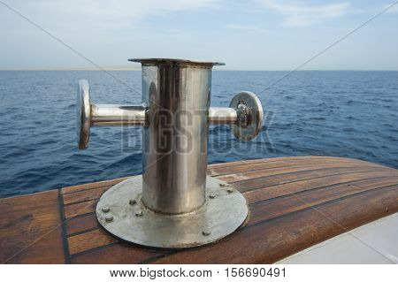 Metal steel capstan post on side teak deck of a luxury motor yacht sailing on tropical ocean