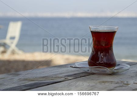 Traditional turkish glass of tea on the old wooden table near sea