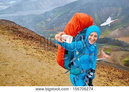 woman hiker photographer taking selfie on the rhyolite mountains background in Iceland