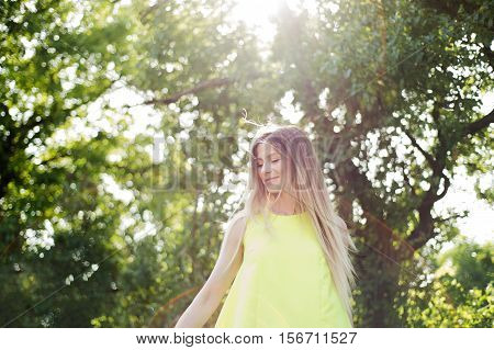 Beautiful young woman with long blowing blonde hair in neon yellow tank top. Sunny summer day.