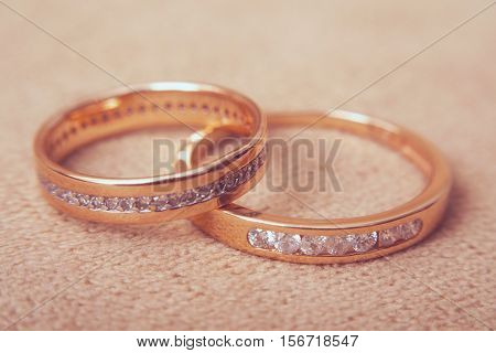 Two beautiful golden wedding rings with brilliants close up, vintage toned. Marriage concept