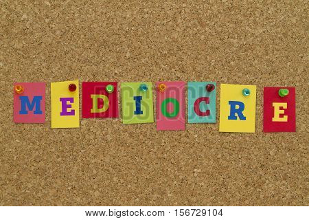 Mediocre word written on colorful sticky notes pinned on cork board.