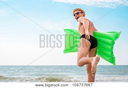 Man in straw hat runs with air swimimg mattress in the sea