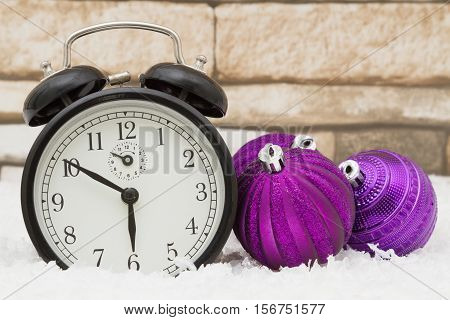 Winter Time Scene Some snow purple Christmas ball ornaments and an alarm clock on weathered bricks
