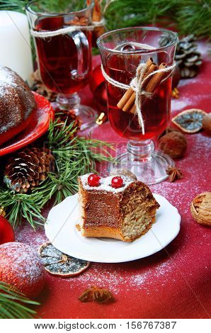 Christmas table setting. Bundt cake pudding sprinkled with sugar powder decorated with red currant and mulled wine.