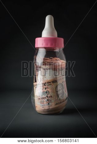 Old Indian rupee notes filled in the feeding bottle. A concept.