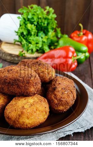 Meat mini-rolls (cutlet) with boiled egg in a clay bowl on dark wooden background.
