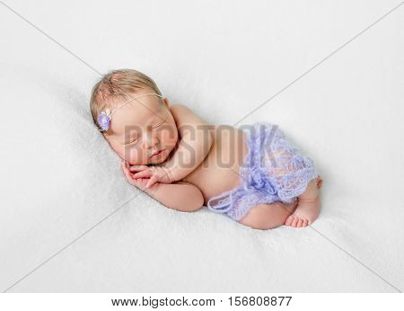 lovely sleeping newborn girl with hands under head in violet knitted panties