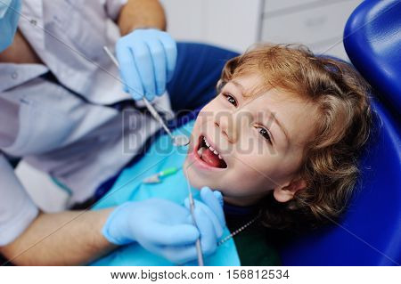 smiling child sitting in a blue chair dental