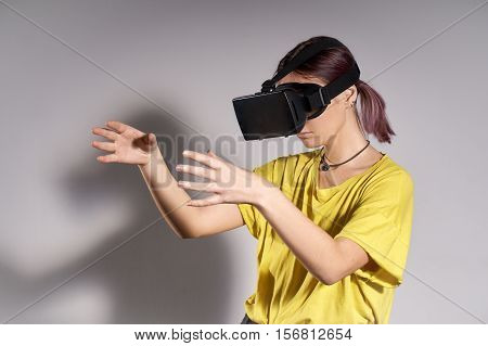 Woman in VR headset looking up and trying to touch objects in virtual reality. VR is a computer technology that simulates a physical presence and allows the user to interact with environment.