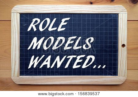 The phrase Role Models Wanted in white text on a used blackboard as a call out for people who can mentor and set standards of behavior