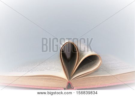 Heart shaped book pages. Old book page decorate to heart shape. Composition of love with open book rolled in heart.