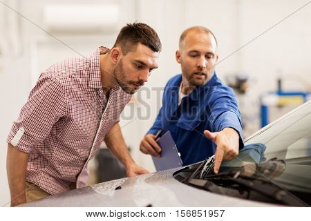 auto service, repair, maintenance and people concept - mechanic checking windshield wiper and man or owner at car shop
