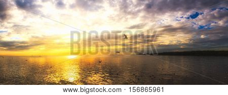 Tranquil scene cloudy sea sunset with seagulls flying at sunset at Bang Poo Recreational Retreat Samut Prakan Thailand.