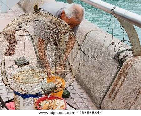 Hong Kong - October 17, 2016: Old Chinese fisherman with his fishing net at the Victoria Harbor of HongKong