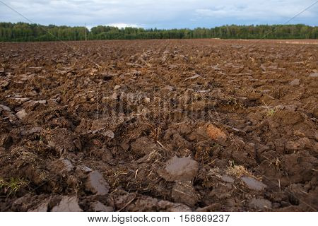 plowed field with tractor traces in spring time, farm soil background.