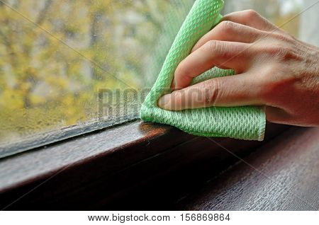 Woman cleaning water condensation on window, close up