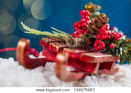 Decorative sleigh with roan-tree and christmas tree branches driving on snow in the background the beautiful bokech balls.