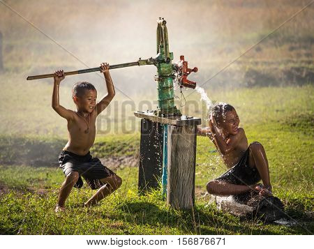 Two young boy rocking groundwater bathe in the hot days Countryside Thailand.