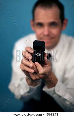 A man proposing and holding up an engagement ring