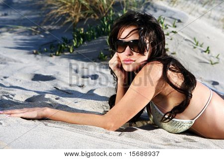 Beautiful model on the beach laying in the sand