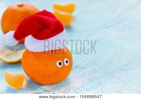 Tangerine with eyes in Santa hat Christmas Xmas New Year concept fresh ripe and sweet mandarin orange clementine tangerine symbol winter holidays