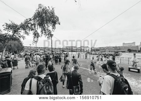 LONDON UNITED KINGDOM - JUL 9 2016: Family and Friends having fun with soap bubbles next to MOMA museum next to Thames riverbank - best adventure and vacancy in United Kingdom