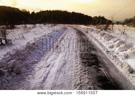 Snow covered winter road with shining streetlights  in rural areas