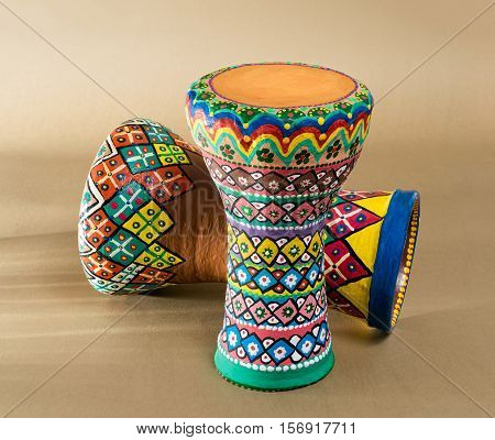 Two decorated colorful pottery goblet drums (chalice drum tarabuka darbuka) on background of wooden table with vanishing shadow lines