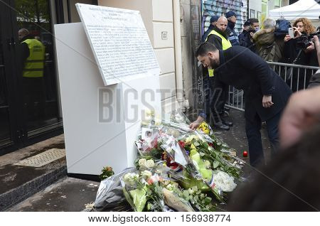 Paris, France - November 13, 2016: Young man posing a flower in front of the memorial for the anniversary of the Bataclan attack