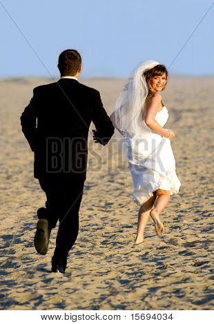 Невеста и жених работает и играя на пляже