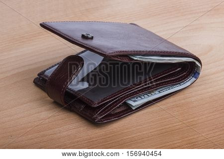 brown leather men's wallet with money on a wooden background