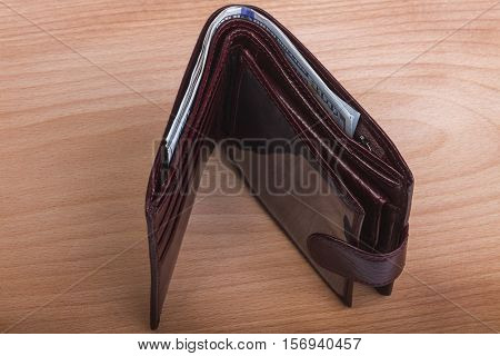 brown leather men's wallet with money on a wooden background