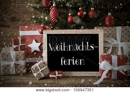 Nostalgic Christmas Card For Seasons Greetings. Christmas Tree With Balls And Snowflakes. Gifts In The Front Of Wooden Background. Chalkboard With German Text Weihnachtsferien Means Christmas Holidays