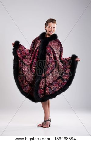 Young beautiful brunette in an embroidered handmade tippet on an isolated background