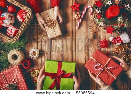 Merry Christmas and Happy Holidays! A mother, father and their daughter prepare Xmas gifts. Baubles, presents, candy with christmas ornaments. Top view. Christmas family traditions.